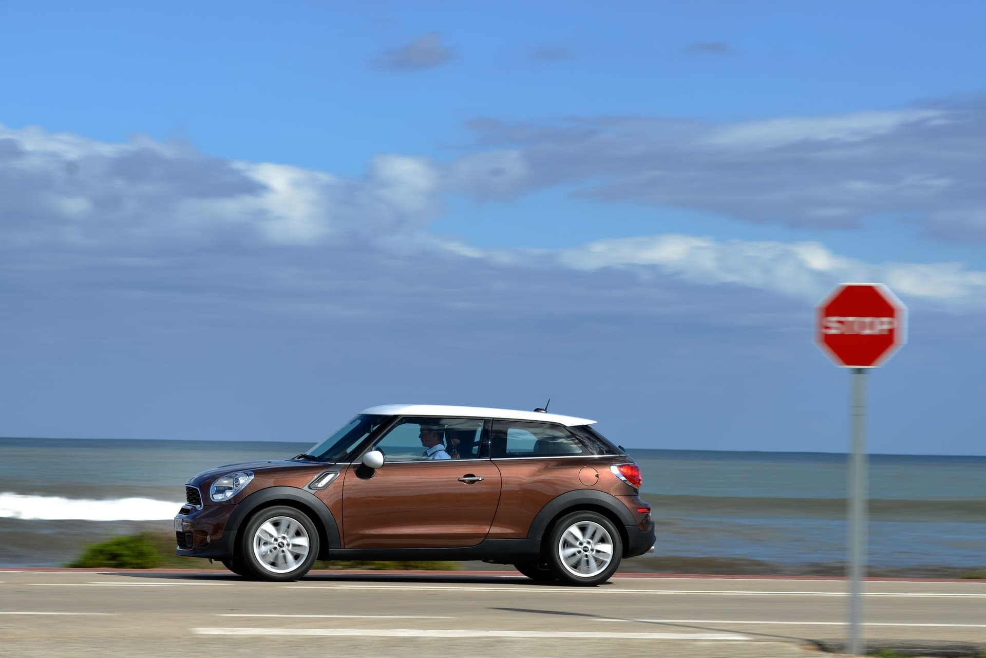 MINI Paceman na nadmorskiej trasie, sylwetka boczna z widokiem na ocean w tle