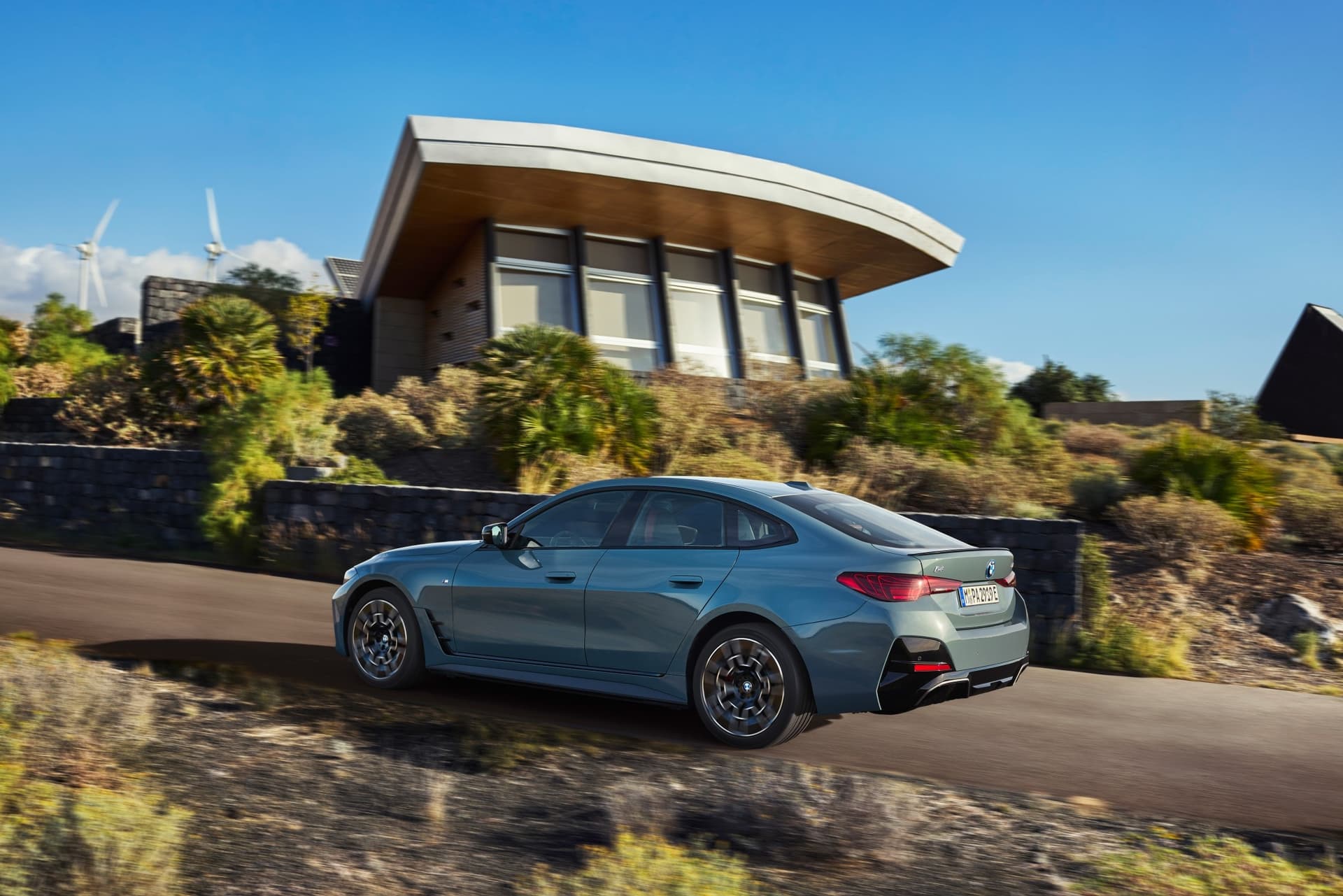 auto_bmw_nowe-samochody_bmw-i4-m60_c50e5624 Tył BMW i4 M60. Samochód podjeżdża pod górę do mansoniery
